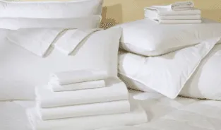A neatly stacked set of white SonderCare bed linens