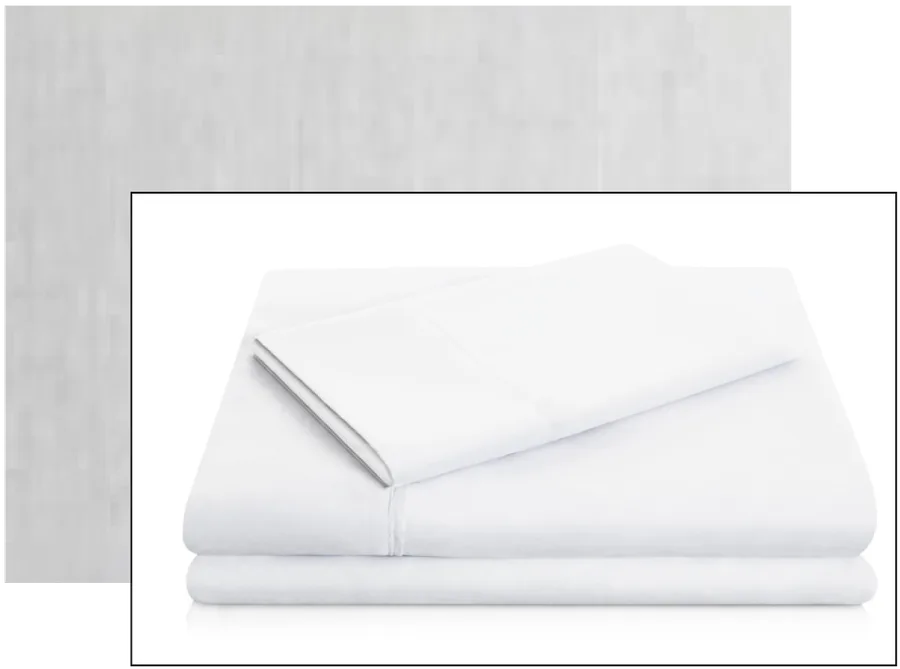 A stack of neatly folded white sheets on a reflective white surface.